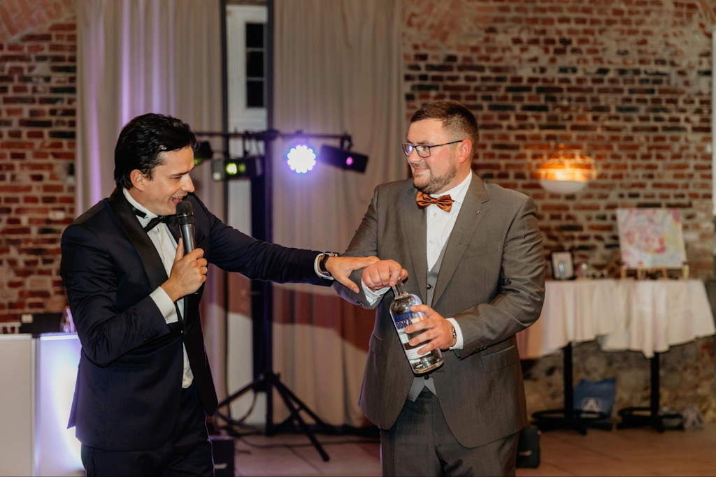 Tamada moderiert mit Mikrofon den Abend einer russischen Hochzeit in einer Loft-Location